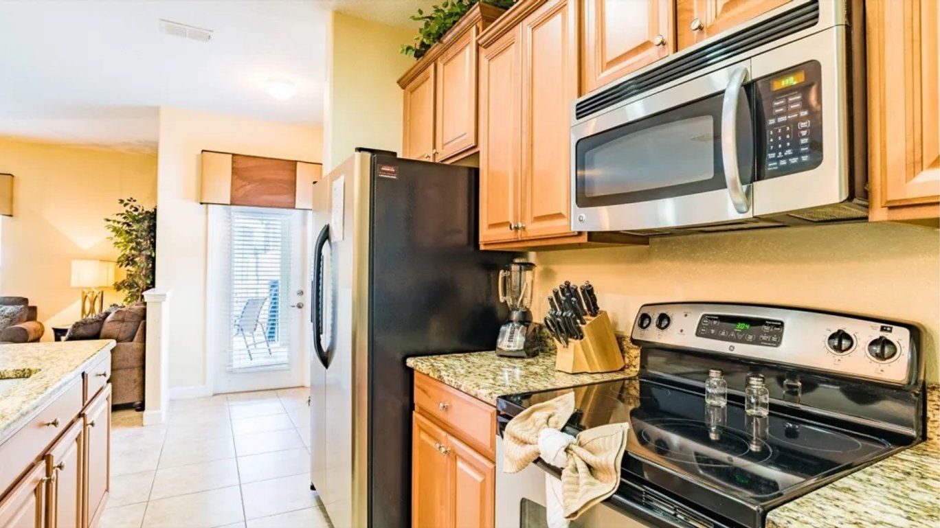 A modern kitchen with stainless steel appliances, wooden cabinets, and a granite countertop.