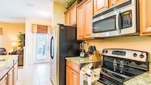 A modern kitchen with stainless steel appliances, wooden cabinets, and a granite countertop. - Paradise Palms - 6166 (Kissimmee)
