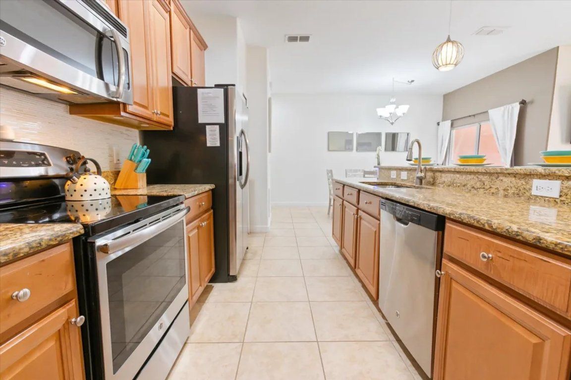 A modern kitchen with stainless steel appliances, wooden cabinets, and a granite countertop.