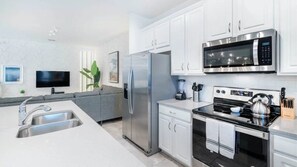 A modern kitchen with white cabinets, stainless steel appliances, a built-in oven, and a microwave. - Solara Resort - 6188 (Kissimmee)