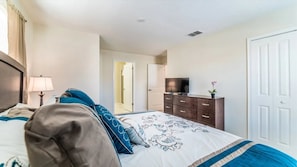 A hotel room with a bed, a television on a dresser, a door, and a window. - Storey Lake - 6278 (Kissimmee)