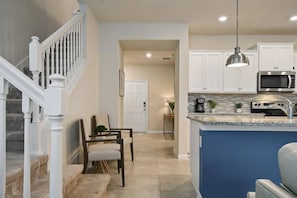 A modern kitchen with white cabinets, a built-in microwave, and a blue island counter. - Windsor Island - 6336 (Davenport)