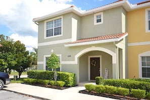A two-story building with a welcoming entrance, a small tree, and well-maintained landscaping. - Paradise Palms - Ocean 279 - 6530 (Kissimmee)