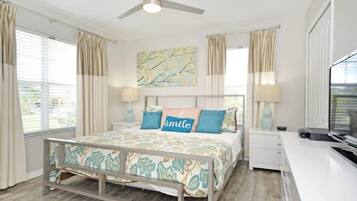 A bedroom with a bed, bedside tables, a ceiling fan, and a window with curtains.