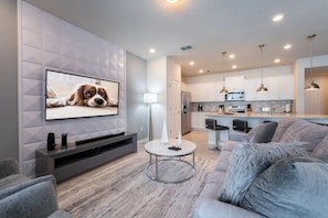 A modern living room with a flat-screen TV, a round coffee table, and a grey sofa. - Windsor Island - 6482 (Davenport)