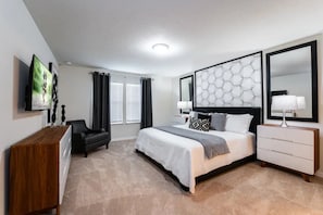 A bedroom with a bed, bedside tables, a TV, a desk, and a chair. - Windsor Island - 6482 (Davenport)