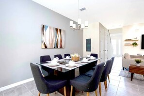 A modern dining area with a rectangular table set for six, surrounded by dark upholstered chairs with wooden legs. - Solara Resort - 6764 (Kissimmee)
