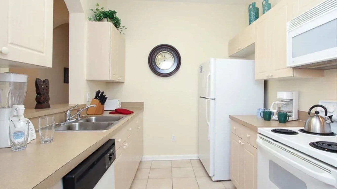 A compact kitchen with a refrigerator, stove, sink, and cabinets.