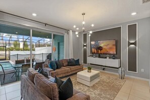 A modern living room with a sofa, coffee table, and a flat-screen TV mounted on the wall. - Windsor Island - 7358 (Davenport)