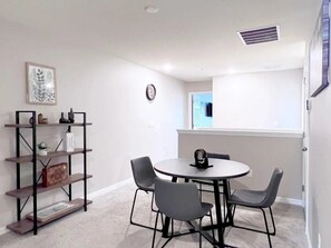 A room with a round table and four chairs, a bookshelf, and a window with a view. - Solara Resort - 7390 (Kissimmee)