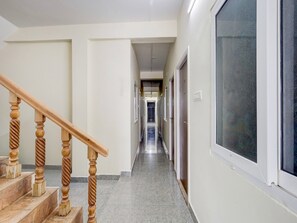 Ein Korridor mit einer Holztreppe links, die zu einer Zwischenebene führt.