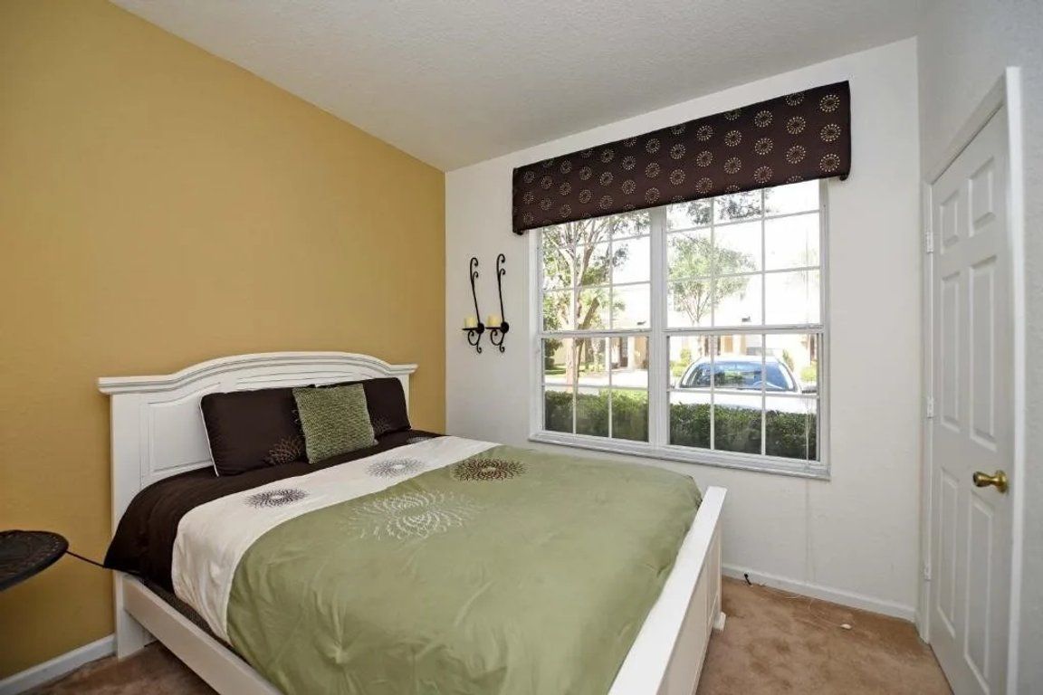 Un dormitorio con una cama, una ventana con vistas al exterior y una puerta.