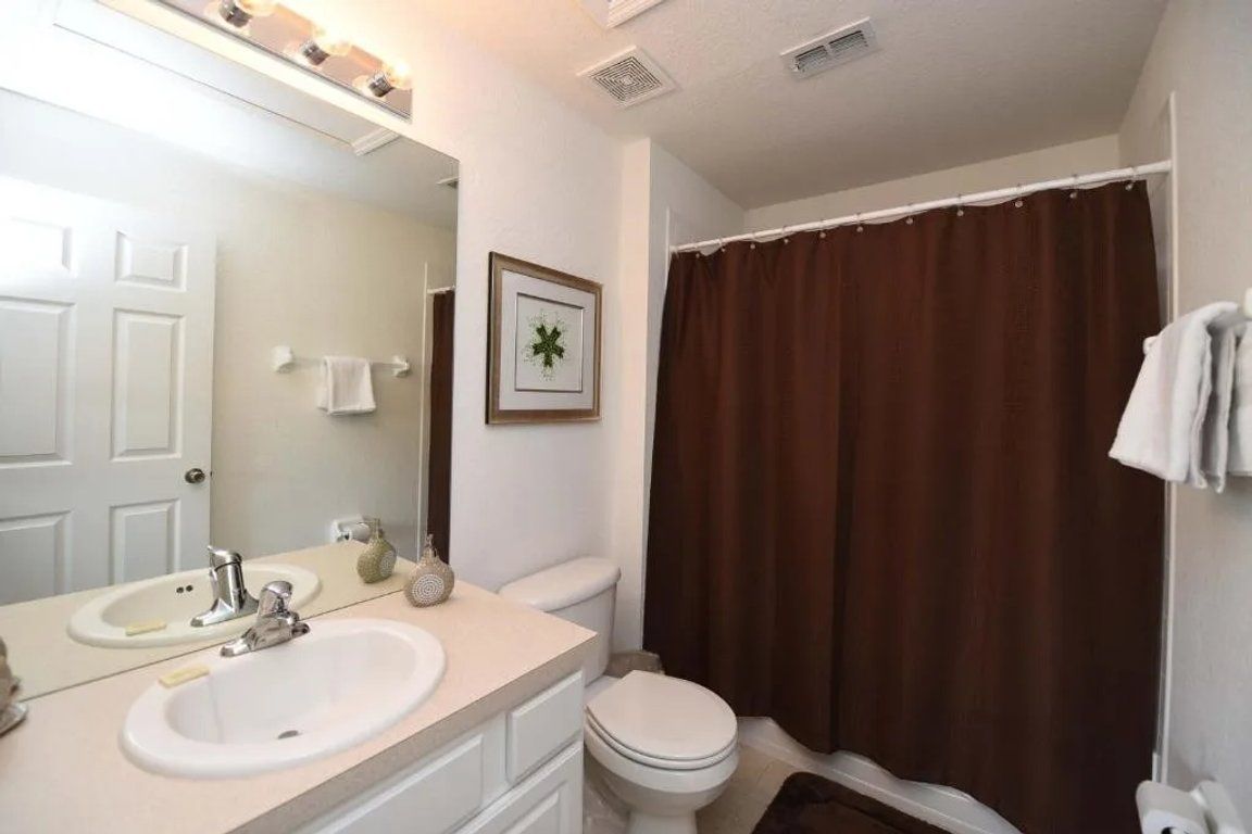 Un baño con lavamanos blanco, inodoro y cortina de ducha.