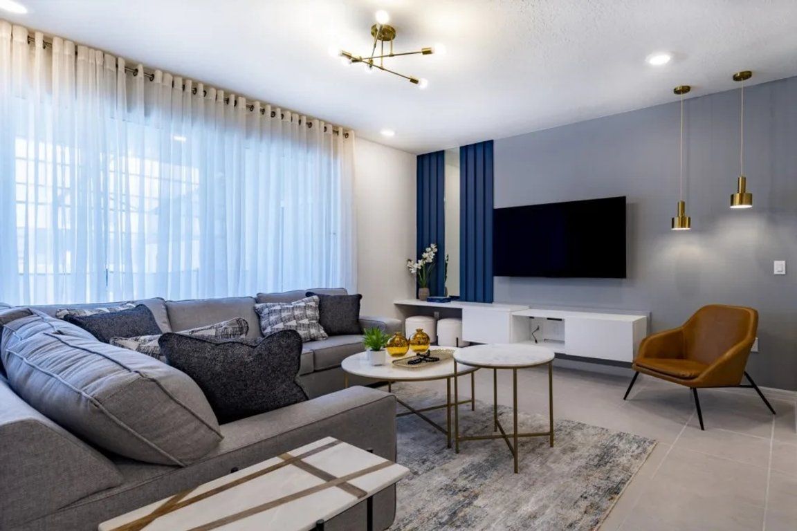 A modern living room with a sectional sofa, a coffee table, a TV, and a chair.
