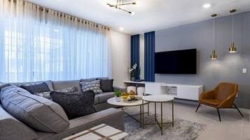 A modern living room with a sectional sofa, a coffee table, a TV, and a chair.