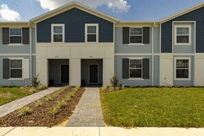 A multi-story residential building with a central entrance, numbered units, and a well-maintained lawn. - Windsor Island - 7856 (Davenport)