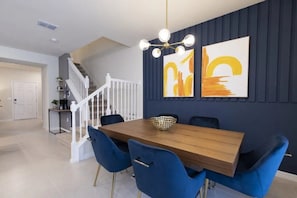 A dining area with a wooden table, blue chairs, and a chandelier. - Windsor Island - 7856 (Davenport)