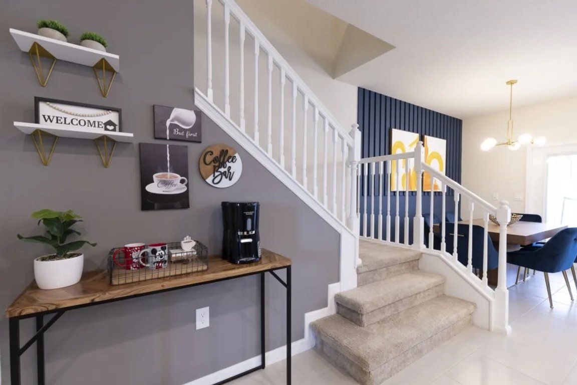 A staircase with a white railing leading to a dining area with blue chairs.