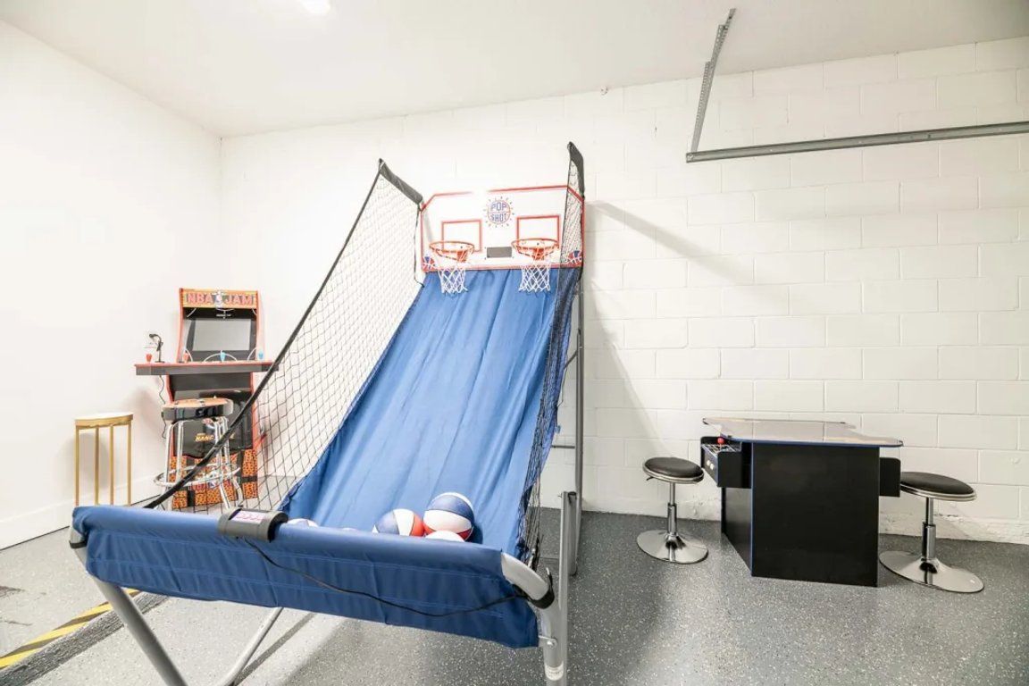 Une pièce avec un toboggan bleu, un panier de basket et une petite table avec des tabourets.
