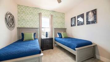 Une chambre avec deux lits, un ventilateur de plafond et une fenêtre avec des rideaux.