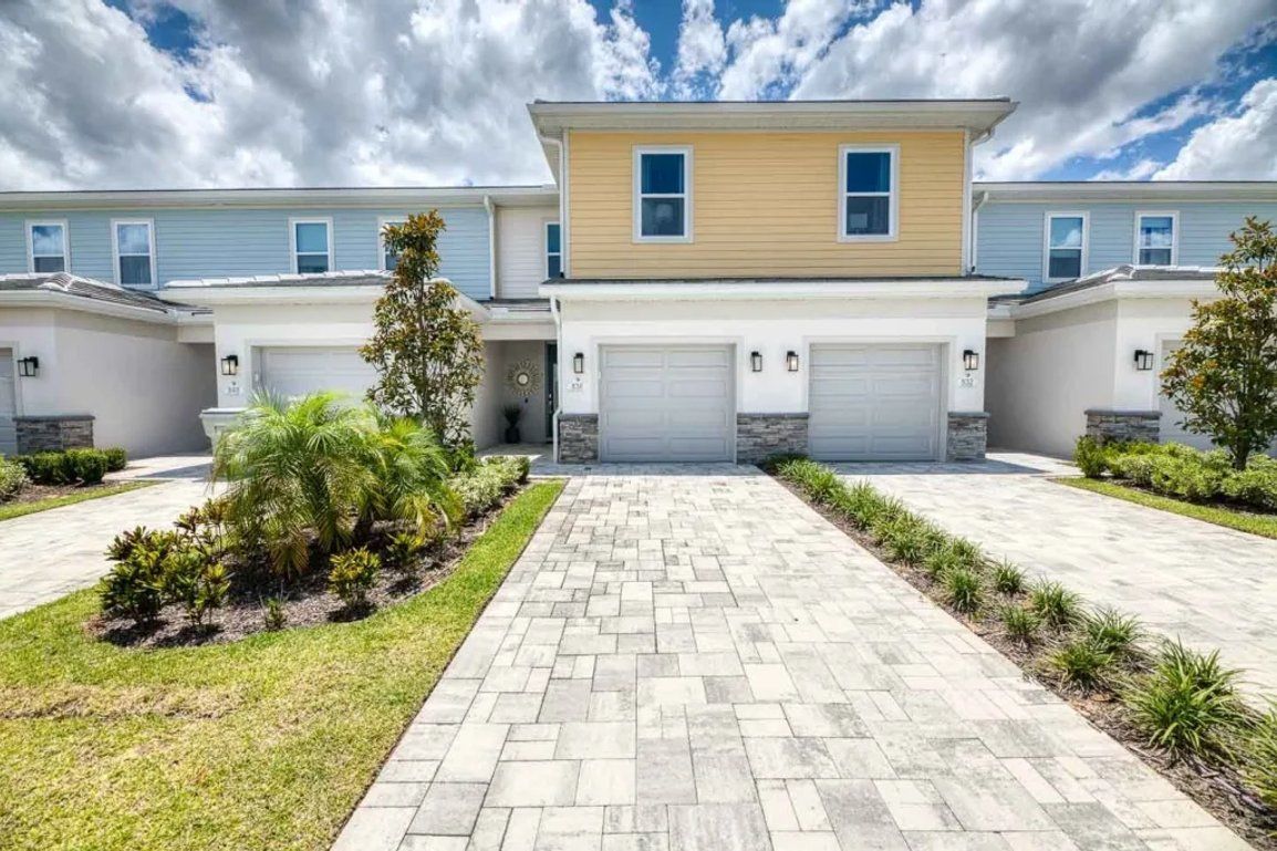 A residential building with a central driveway, multiple garages, and a symmetrical facade.