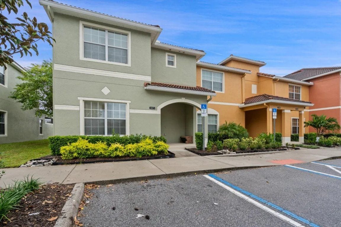 A multi-story residential building with a parking lot in front.