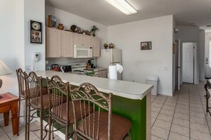A kitchen with a central island, wooden chairs, a microwave, a refrigerator, and a sink. - Windsor Palms - 11478 (Kissimmee)
