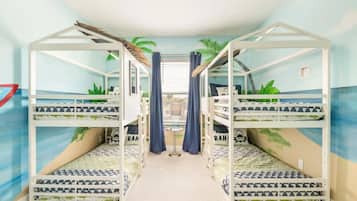 A room with bunk beds, a small table, and curtains.