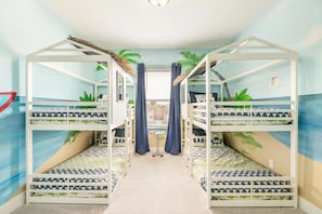 Una habitación con literas, una mesita pequeña y cortinas.