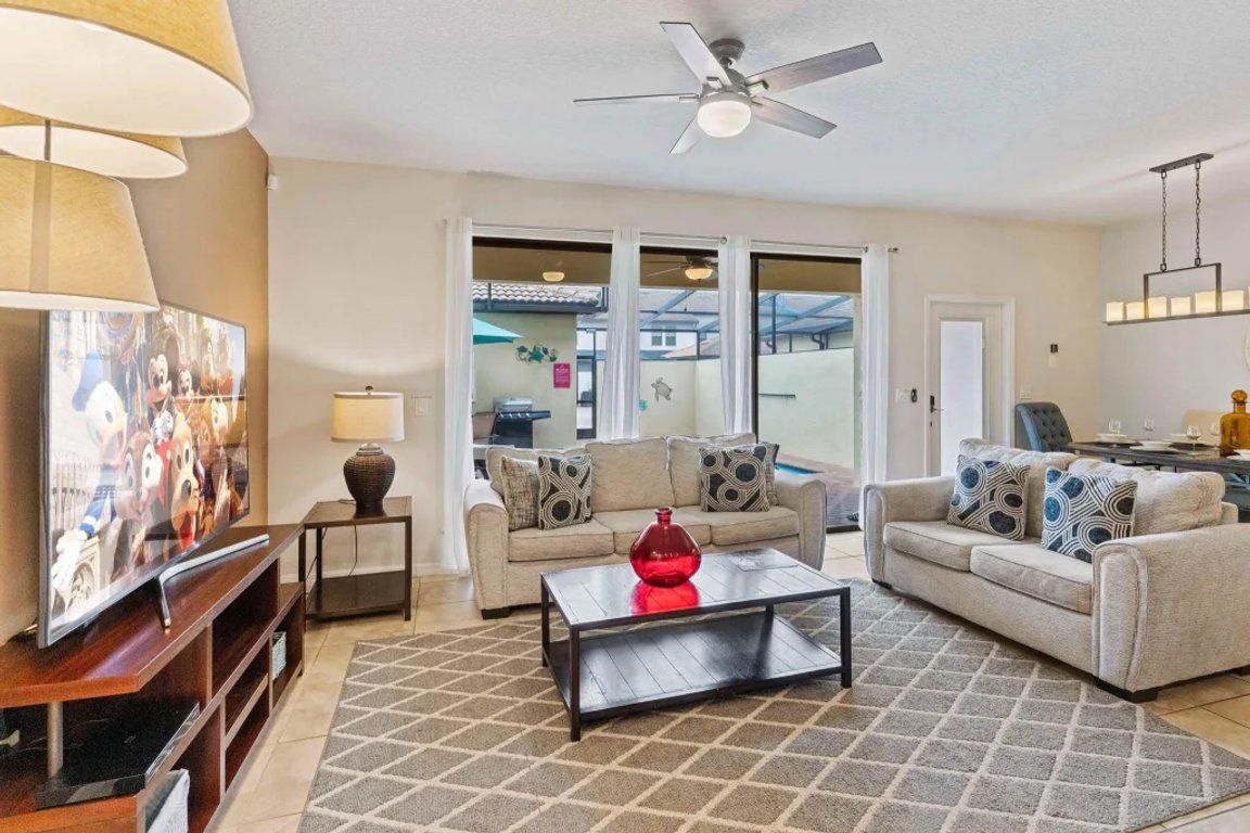 A living room with a sofa, coffee table, TV, and ceiling fan.
