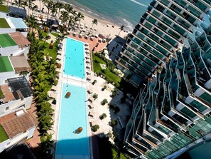 A resort with a large pool, beach area, and modern buildings. - Luxury Oceanfront Corner Condo | Icon Vallarta (Puerto Vallarta)
