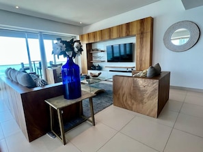 Ein modernes Wohnzimmer mit einer Couch, einem Couchtisch und einem an der Wand montierten Fernseher.