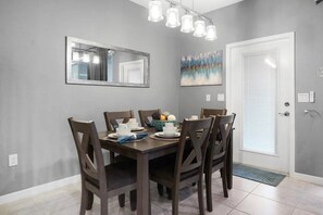 A dining area with a table set for four, chairs, a mirror, and a door with a window. - Windsor Island - 11653 (Davenport)