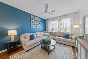 A living room with a blue accent wall, a ceiling fan, a sofa set, a coffee table, and a lamp. - Windsor Palms - 29095 (Kissimmee)