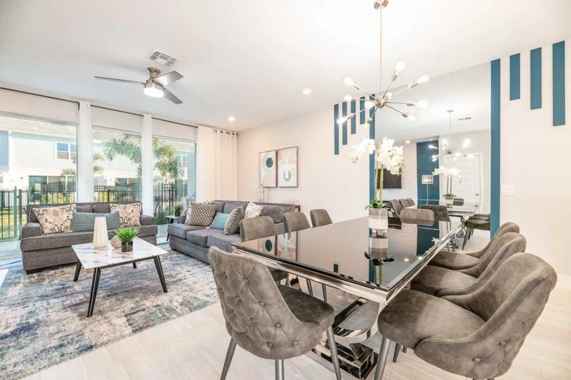 Un salon moderne comprenant un canapé, une table basse et un coin repas avec des chaises.