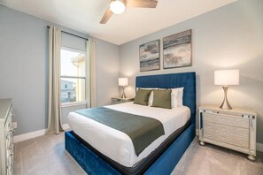 Un dormitorio con cama, mesitas de noche, ventilador de techo y obras de arte en la pared.
