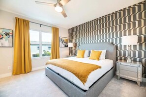 Un dormitorio moderno con una cama grande, un ventilador de techo, un papel tapiz decorativo y una ventana con cortinas.