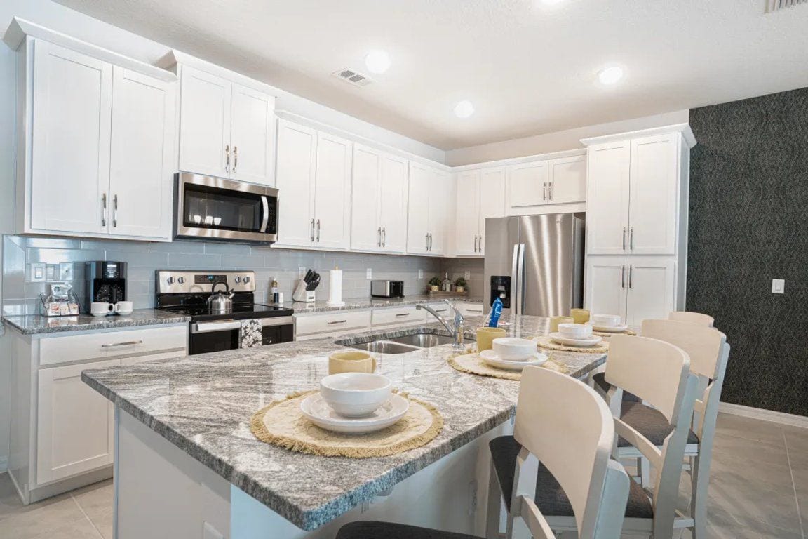 A modern kitchen with white cabinetry, stainless steel appliances, and a granite countertop.