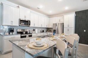 A modern kitchen with white cabinetry, stainless steel appliances, and a granite countertop. - Solara Resort - 28902 (Kissimmee)
