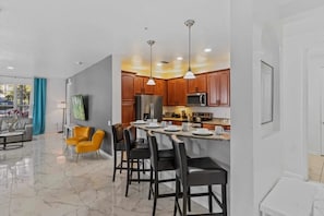 A modern kitchen with wooden cabinets, a central island, and a dining area with chairs. - Vista Cay - 28983 (Orlando)