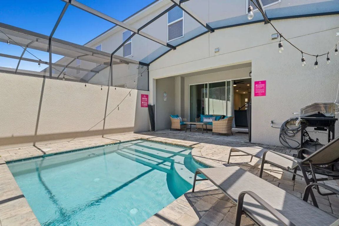 An outdoor swimming pool with lounge chairs and a covered seating area.