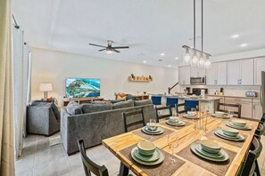 A modern living room with a dining area, a kitchen, and a large painting on the wall. - Solara Resort - 29105 (Kissimmee)