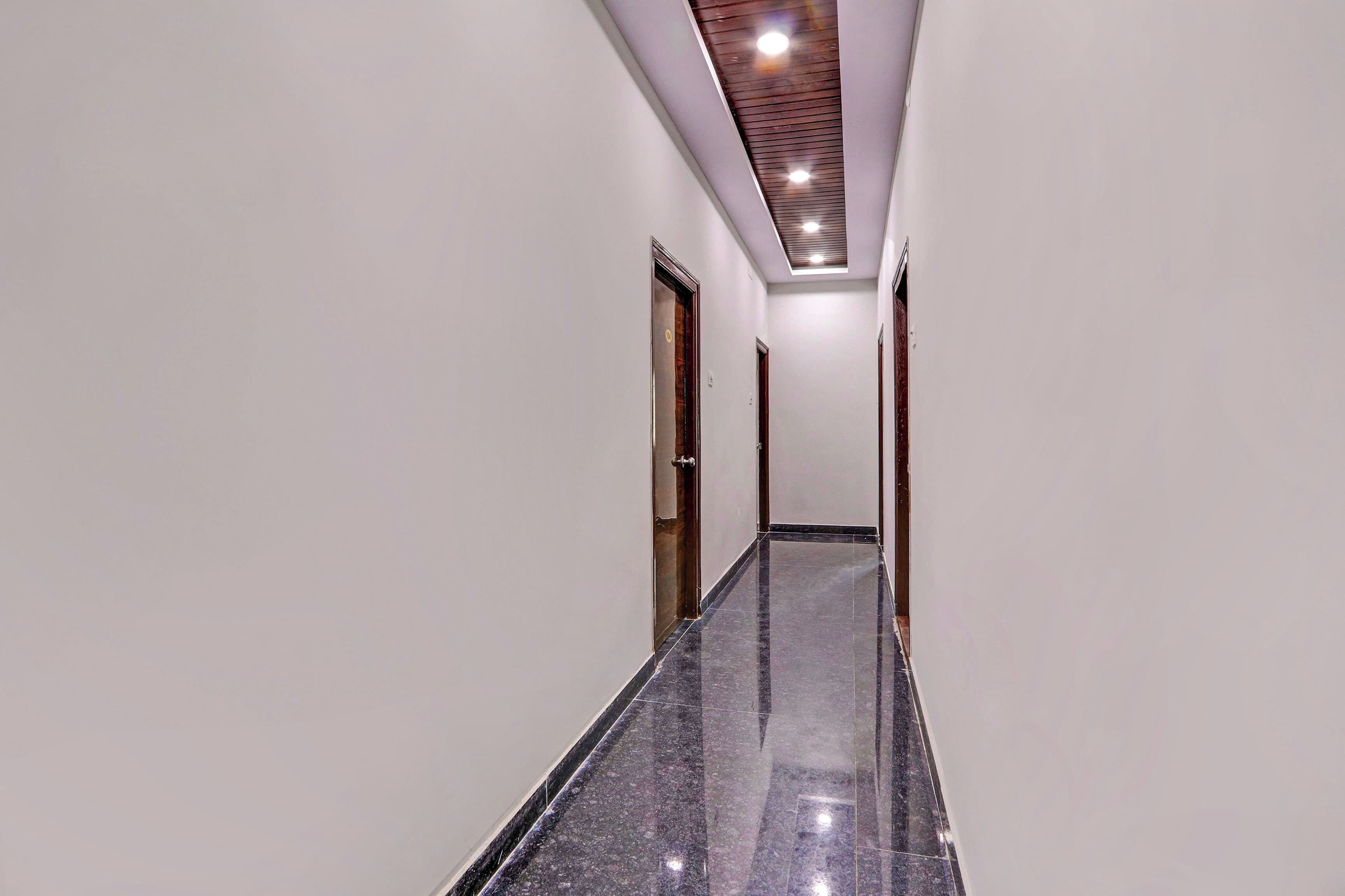 Un pasillo con piso de mármol pulido, puertas de madera e iluminación empotrada en el techo.