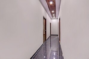 Un pasillo con piso de mármol pulido, puertas de madera e iluminación empotrada en el techo.
