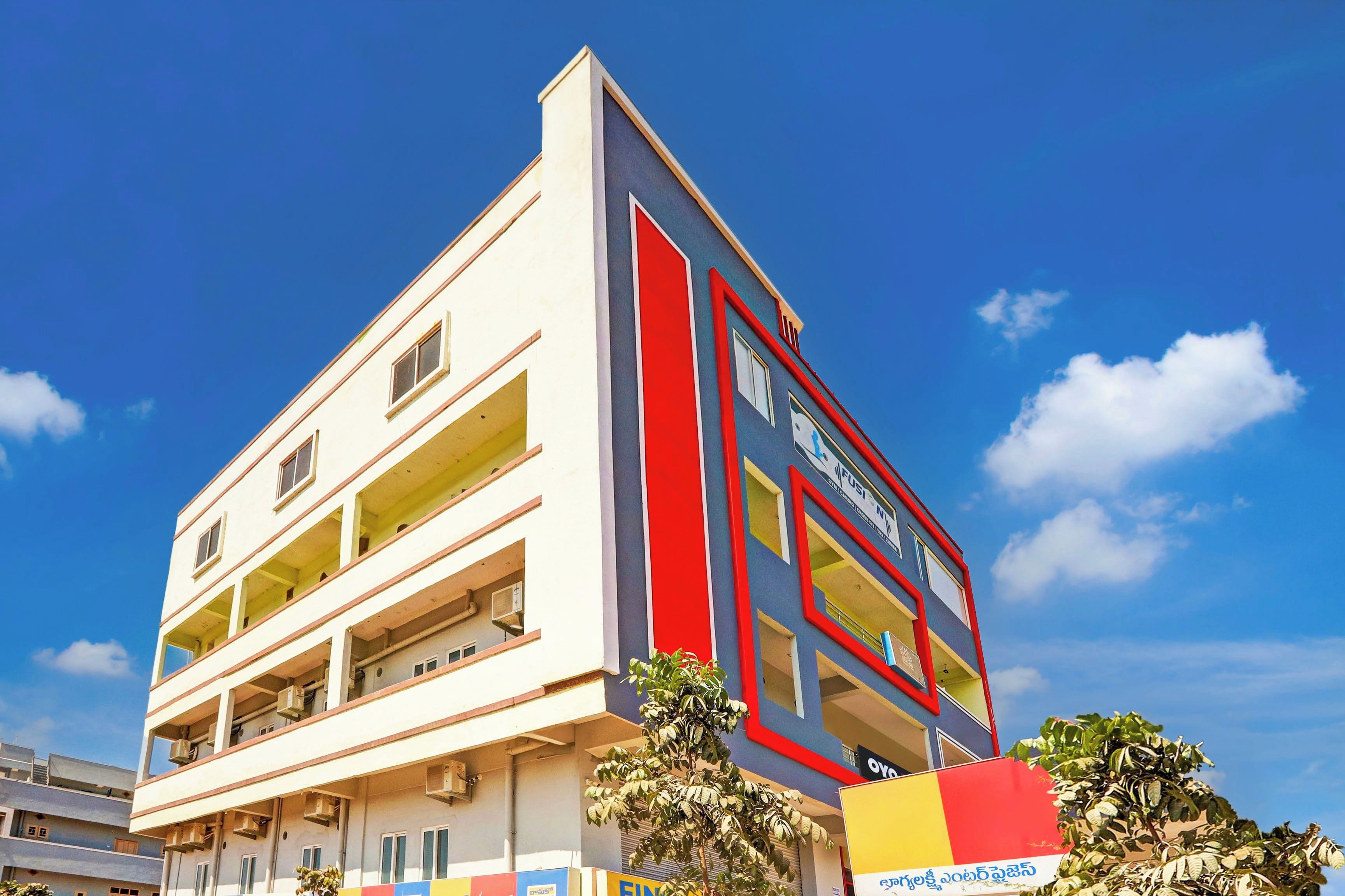 Un edificio de varios pisos con fachada plana, balcones y un cielo azul despejado al fondo.