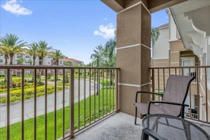 A balcony with a view of a landscaped area and a building in the background. - Vista Cay - 1752 (Orlando)