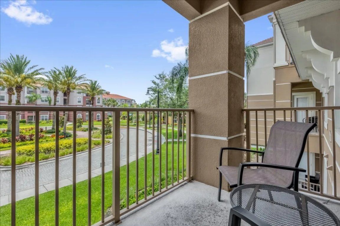 Ein Balkon mit Blick auf eine angelegte Grünfläche und ein Gebäude im Hintergrund.