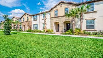 A row of townhouses with a well-maintained lawn and palm trees.