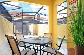 An outdoor patio with a table and chairs, a potted plant, and a warning sign. - Paradise Palms - Ocean 241 - 5745 (Kissimmee)