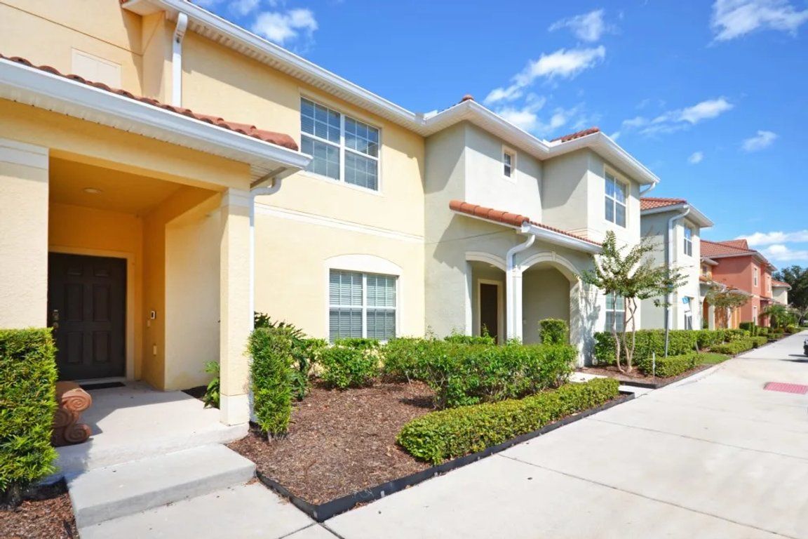 A residential building with a front porch, a driveway, and a landscaped garden.